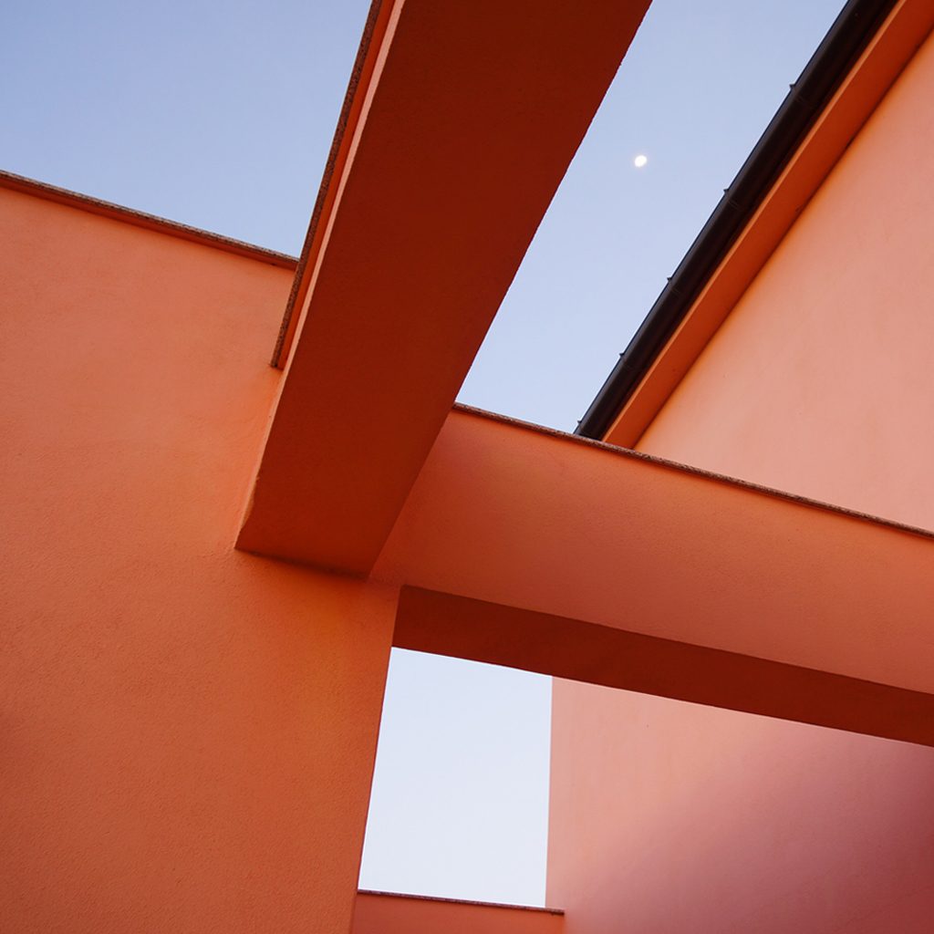 Rote Wandscheiben und Dachüberstand vor blauem Himmel