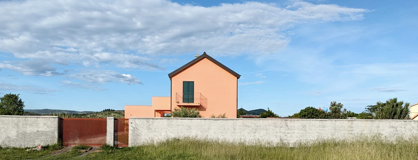 Terrakottafarbenes Einfamilienhaus auf dem Land unter blauem Himmel